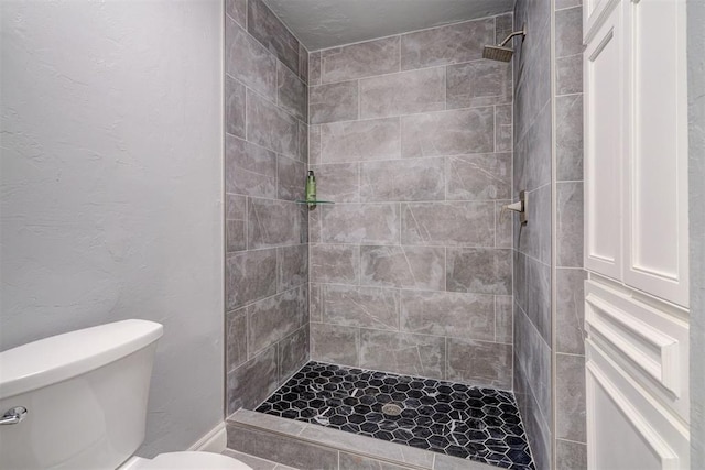 bathroom with toilet and a tile shower