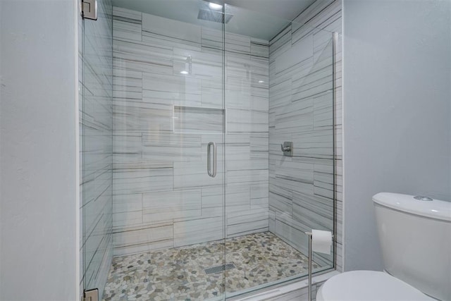 bathroom with toilet and a shower with shower door