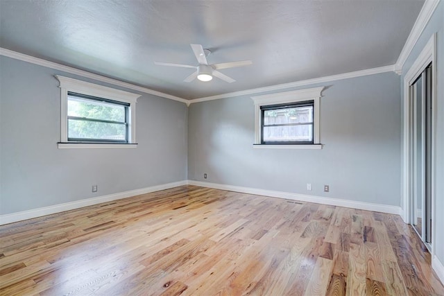 unfurnished room featuring light wood-type flooring, crown molding, and a wealth of natural light