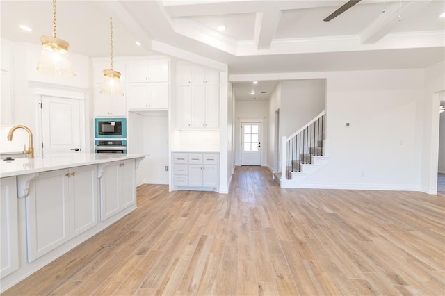 kitchen featuring oven, hanging light fixtures, black microwave, and white cabinets