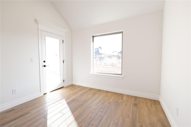 empty room with vaulted ceiling and light hardwood / wood-style floors