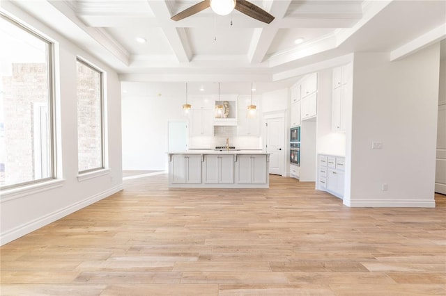 kitchen with decorative light fixtures, a kitchen island with sink, light hardwood / wood-style flooring, and white cabinets