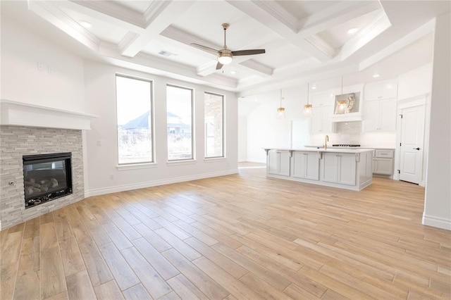 unfurnished living room with beamed ceiling, ceiling fan, and light hardwood / wood-style floors