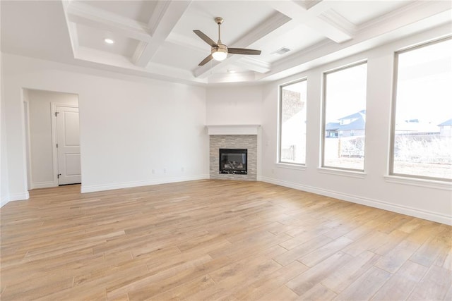 unfurnished living room featuring beamed ceiling, a healthy amount of sunlight, a fireplace, and light hardwood / wood-style floors