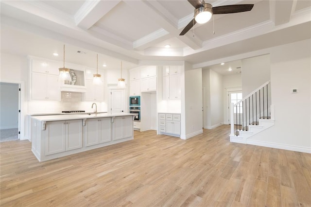 kitchen with built in microwave, light wood finished floors, stainless steel oven, and white cabinets