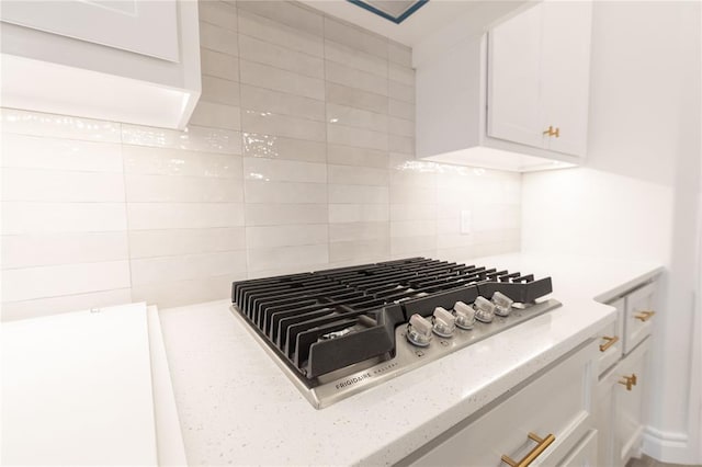 room details featuring stainless steel gas cooktop, tasteful backsplash, light stone counters, and white cabinets