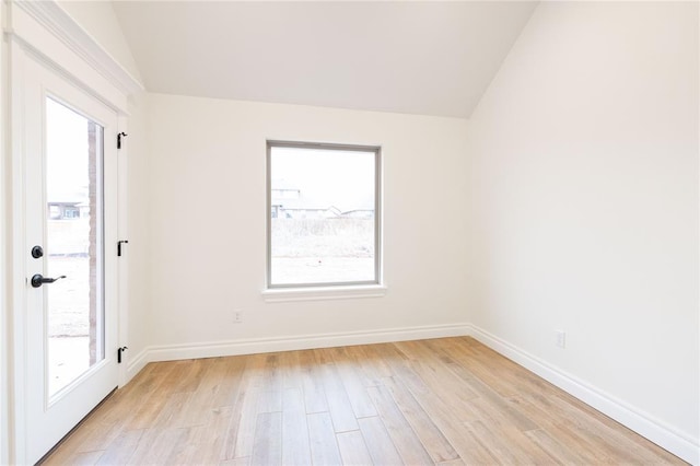 empty room featuring lofted ceiling, baseboards, and light wood finished floors