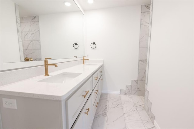 bathroom with marble finish floor, double vanity, a sink, and recessed lighting