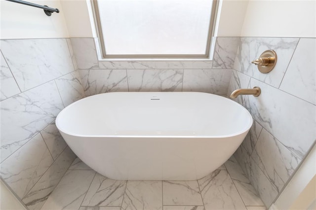 bathroom with a freestanding bath and marble finish floor