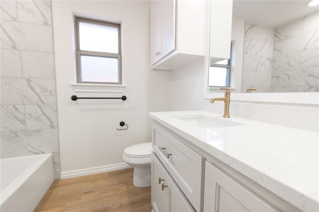 full bath with toilet, baseboards, wood finished floors, and vanity