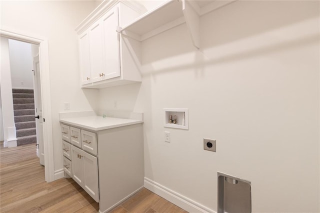 clothes washing area featuring cabinet space, baseboards, hookup for a washing machine, light wood-type flooring, and electric dryer hookup