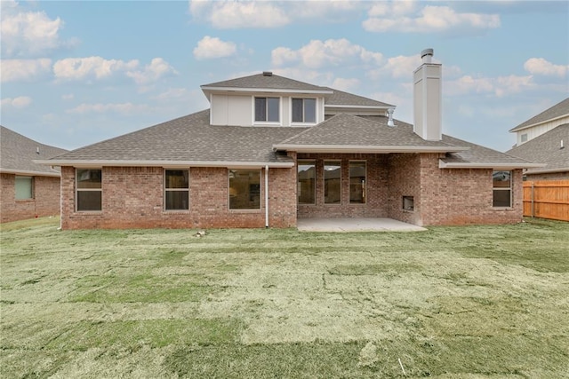 back of house with brick siding, a shingled roof, fence, a chimney, and a patio area