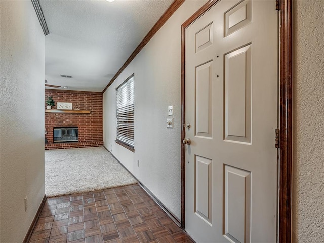 hallway featuring a textured ceiling, dark carpet, and ornamental molding