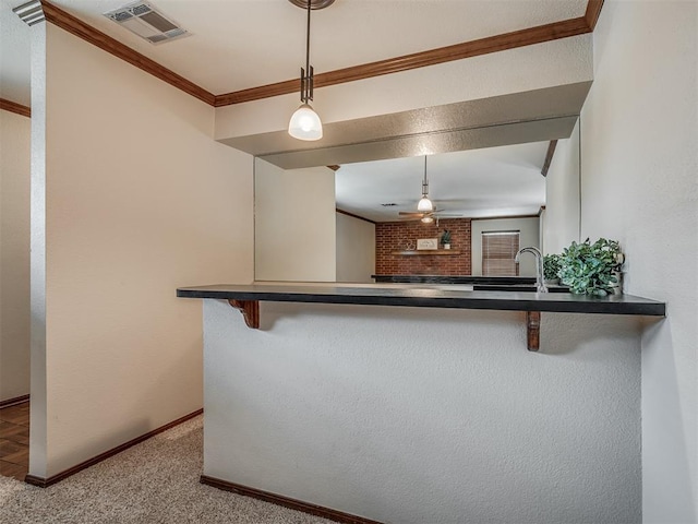 kitchen with kitchen peninsula, a kitchen bar, ceiling fan, crown molding, and hanging light fixtures