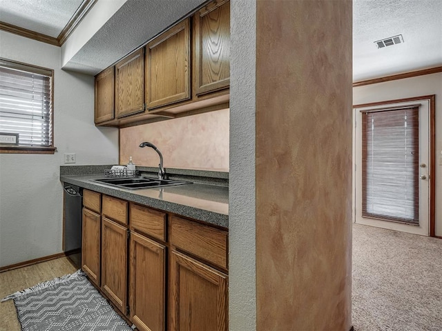 kitchen featuring dishwasher, crown molding, sink, carpet flooring, and a textured ceiling