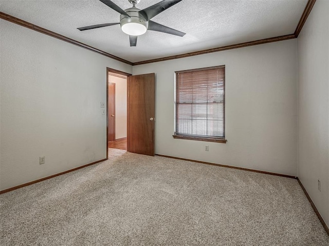 spare room featuring ceiling fan, light colored carpet, a textured ceiling, and crown molding