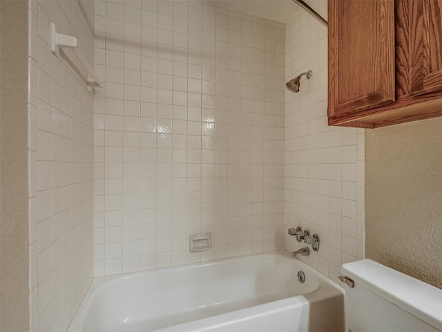 bathroom featuring toilet and tiled shower / bath