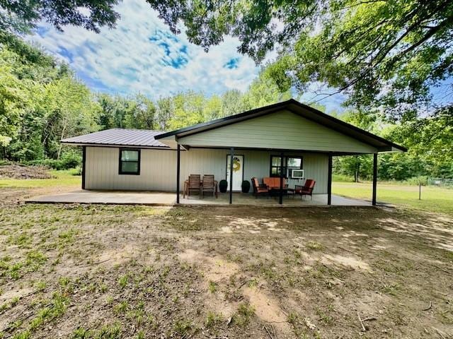 rear view of property with an outdoor living space and a patio