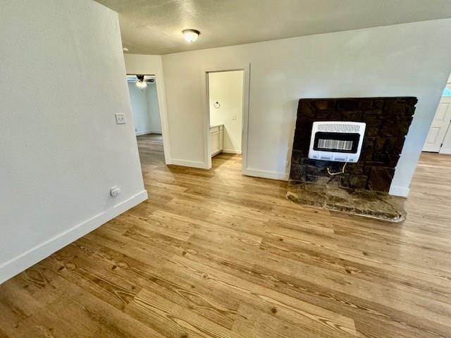 unfurnished living room featuring ceiling fan, light hardwood / wood-style floors, a fireplace, and heating unit