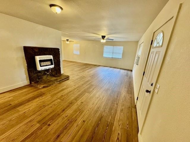 unfurnished living room featuring heating unit, ceiling fan, and hardwood / wood-style floors