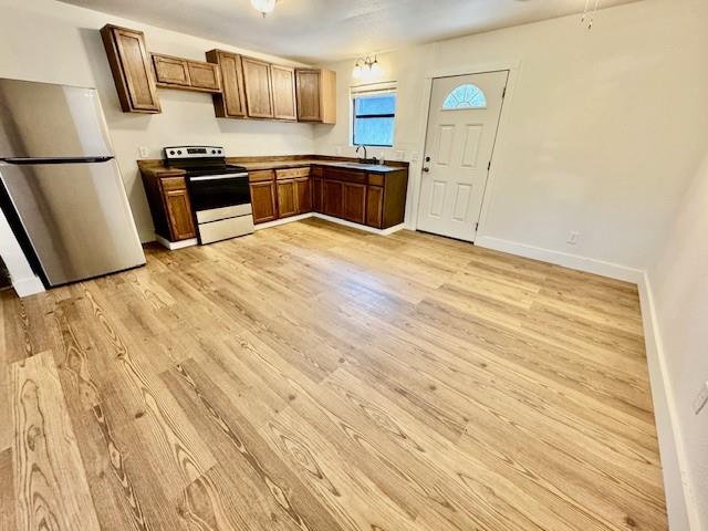 kitchen featuring stainless steel fridge, electric range oven, light hardwood / wood-style floors, and sink