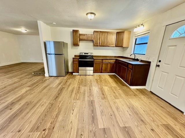 kitchen with light wood-type flooring, sink, and appliances with stainless steel finishes