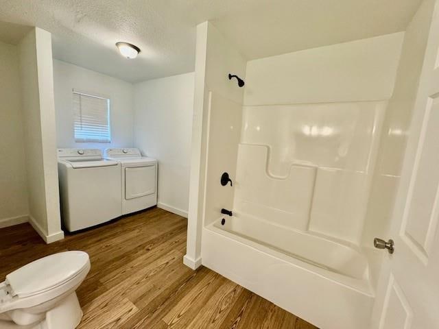 bathroom featuring bathing tub / shower combination, a textured ceiling, toilet, washer and clothes dryer, and hardwood / wood-style flooring