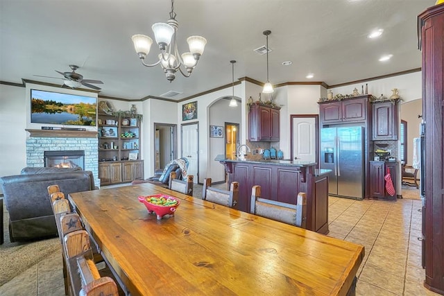 21321 E 1290th Rd, Sentinel, OK 73664 - tiled dining space featuring a fireplace, ceiling fan with notable chandelier, and ornamental molding
