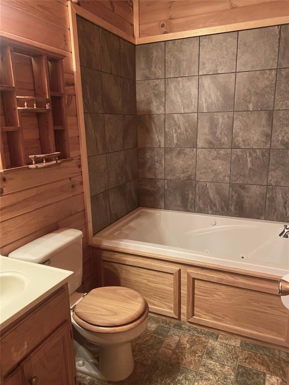 bathroom featuring vanity, wood walls, toilet, and a bath