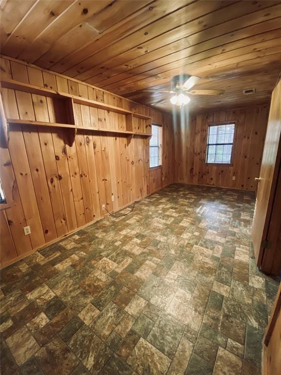 unfurnished room with wooden walls, ceiling fan, and wooden ceiling