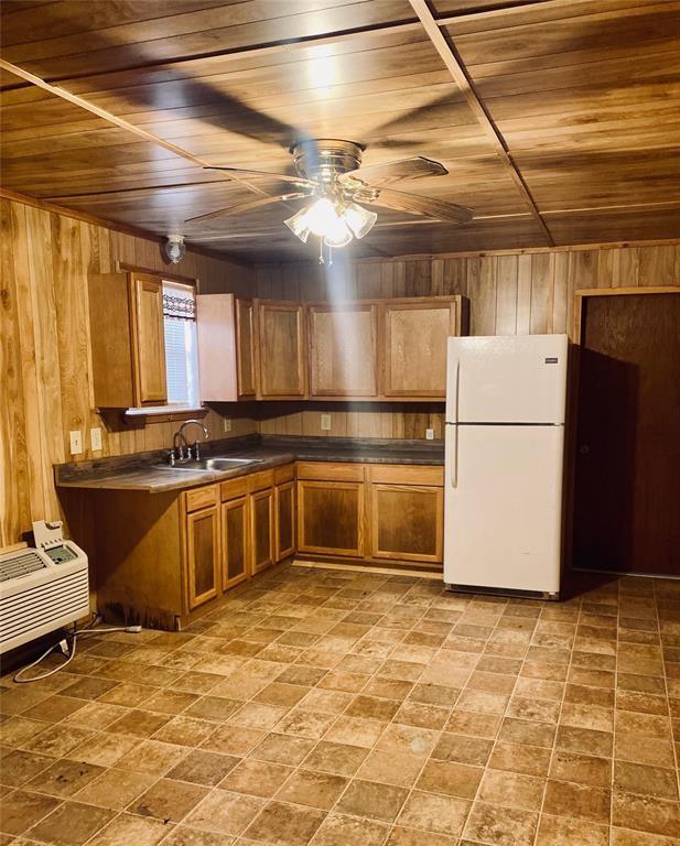 kitchen with wood walls, white fridge, and wood ceiling