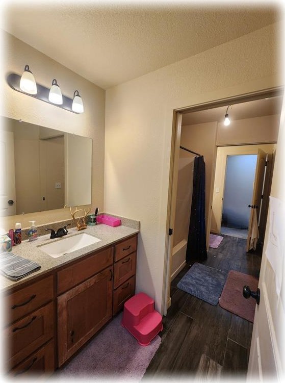 bathroom with hardwood / wood-style floors, vanity, a textured ceiling, and curtained shower