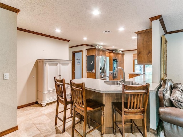 kitchen featuring kitchen peninsula, stainless steel fridge, sink, and a textured ceiling