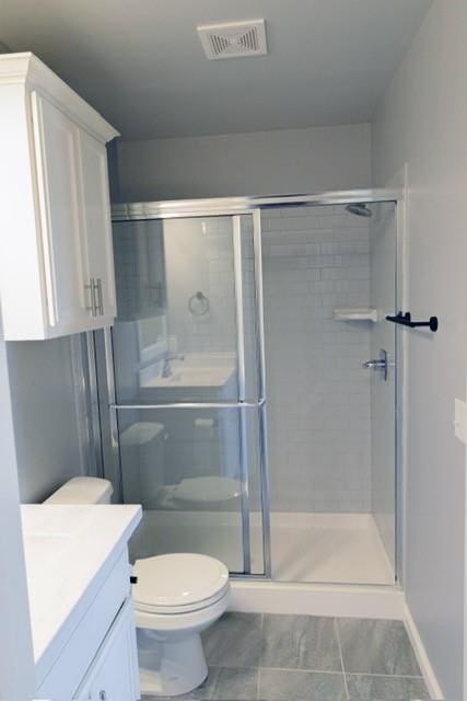 bathroom featuring vanity, toilet, and a shower with shower door