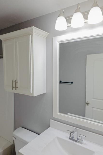 bathroom with vanity, a bath, and toilet