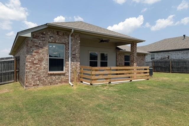 back of property with ceiling fan and a yard