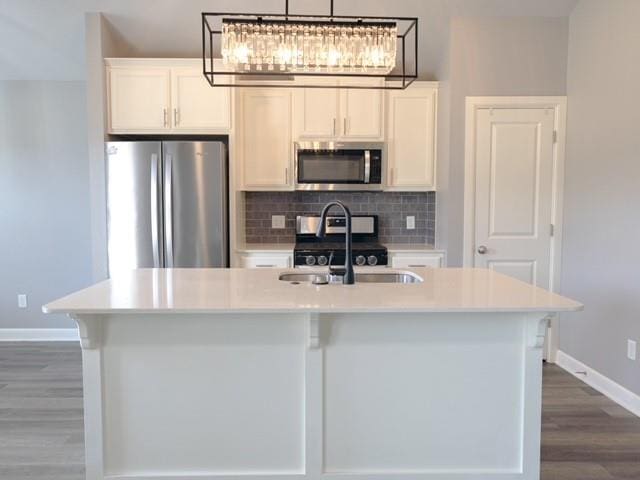 kitchen featuring white cabinets, stainless steel appliances, a kitchen island with sink, and sink