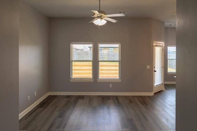 spare room with ceiling fan, a healthy amount of sunlight, and dark wood-type flooring