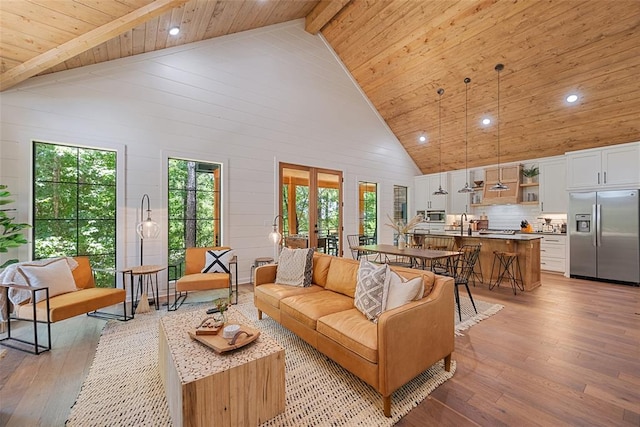 living room featuring high vaulted ceiling, sink, light hardwood / wood-style flooring, beamed ceiling, and wood ceiling