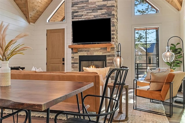 interior space featuring a stone fireplace, wood-type flooring, high vaulted ceiling, and wooden ceiling