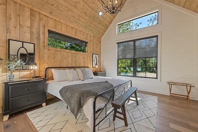 bedroom with wooden walls, wood ceiling, high vaulted ceiling, and light hardwood / wood-style flooring