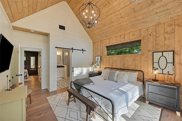 bedroom featuring a barn door, high vaulted ceiling, light hardwood / wood-style floors, and ensuite bath