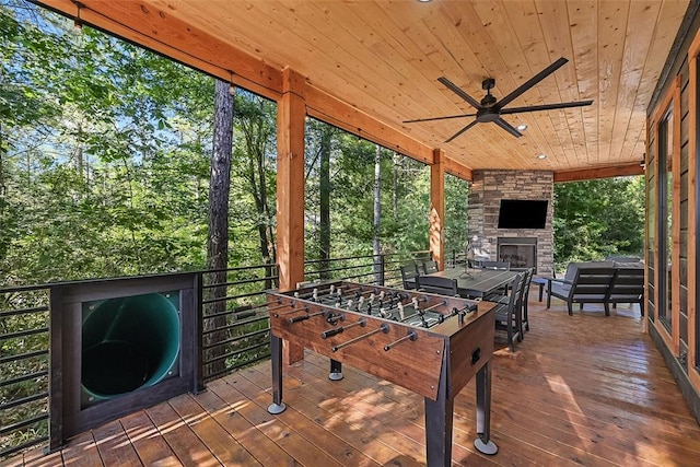 rec room featuring an outdoor stone fireplace, ceiling fan, wood-type flooring, and wood ceiling