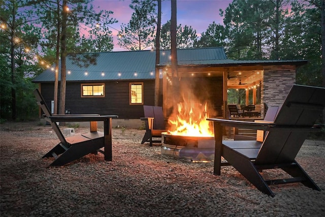 back house at dusk with a patio area, ceiling fan, and an outdoor fire pit