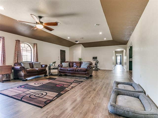 living room featuring hardwood / wood-style floors, ceiling fan, lofted ceiling, and a textured ceiling