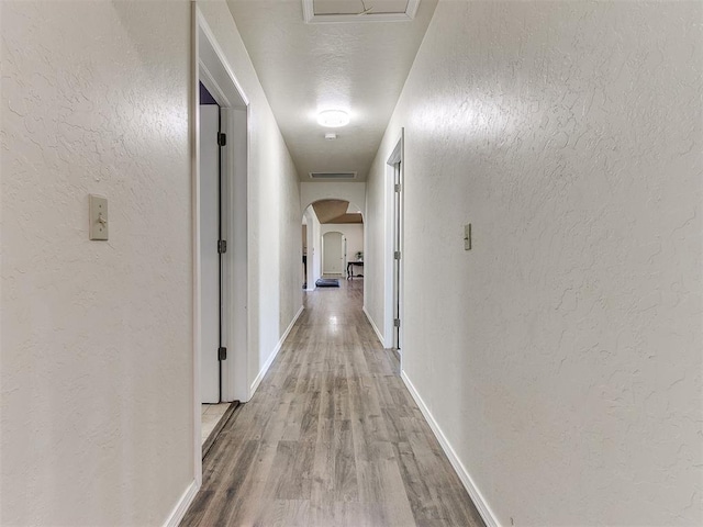 hall featuring light hardwood / wood-style floors and a textured ceiling