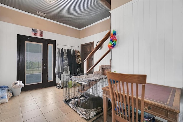 dining room with wooden walls, light tile patterned floors, and ornamental molding