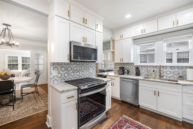 kitchen featuring white cabinets, sink, hanging light fixtures, decorative backsplash, and stainless steel appliances