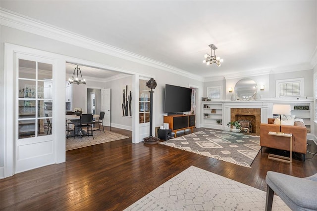 living room featuring a tile fireplace, dark hardwood / wood-style floors, a chandelier, and crown molding