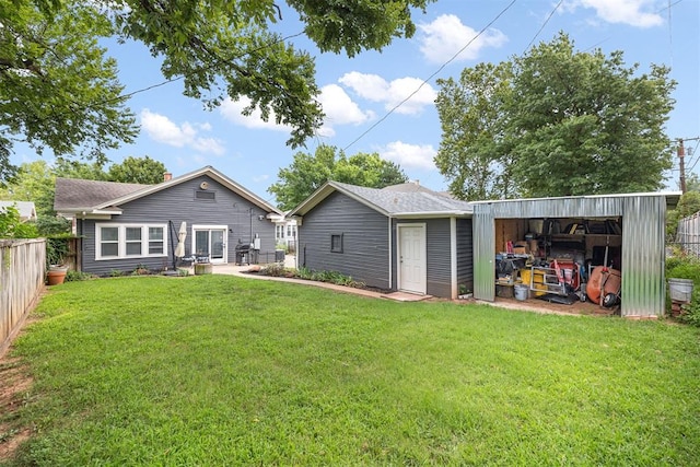 rear view of property featuring a lawn and an outdoor structure